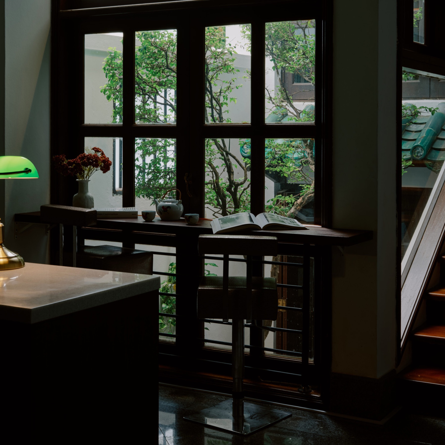 A reading table beside timber windows in a conserved shophouse